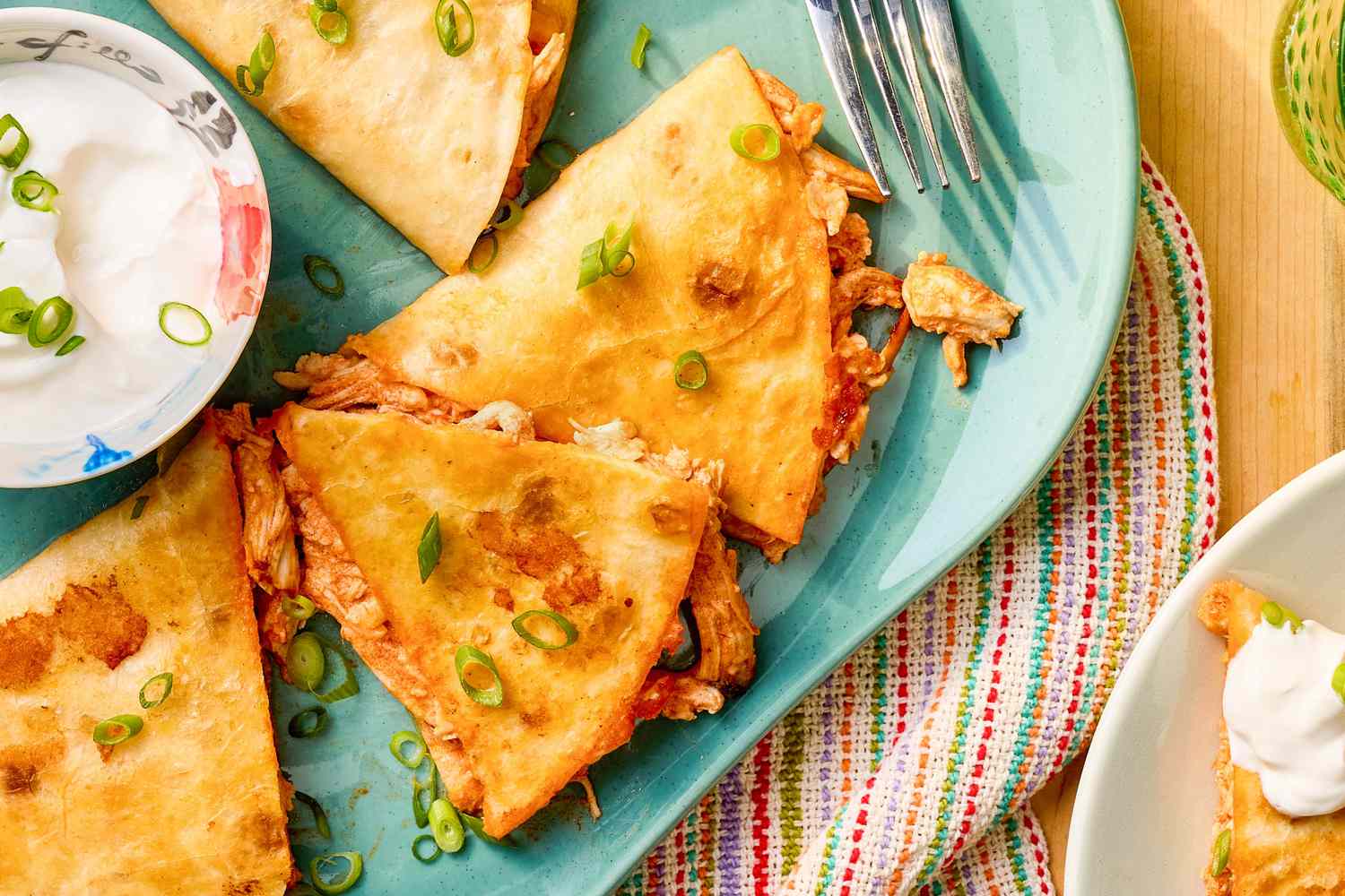 Quesadillas on a plate with a small bowl of sour cream