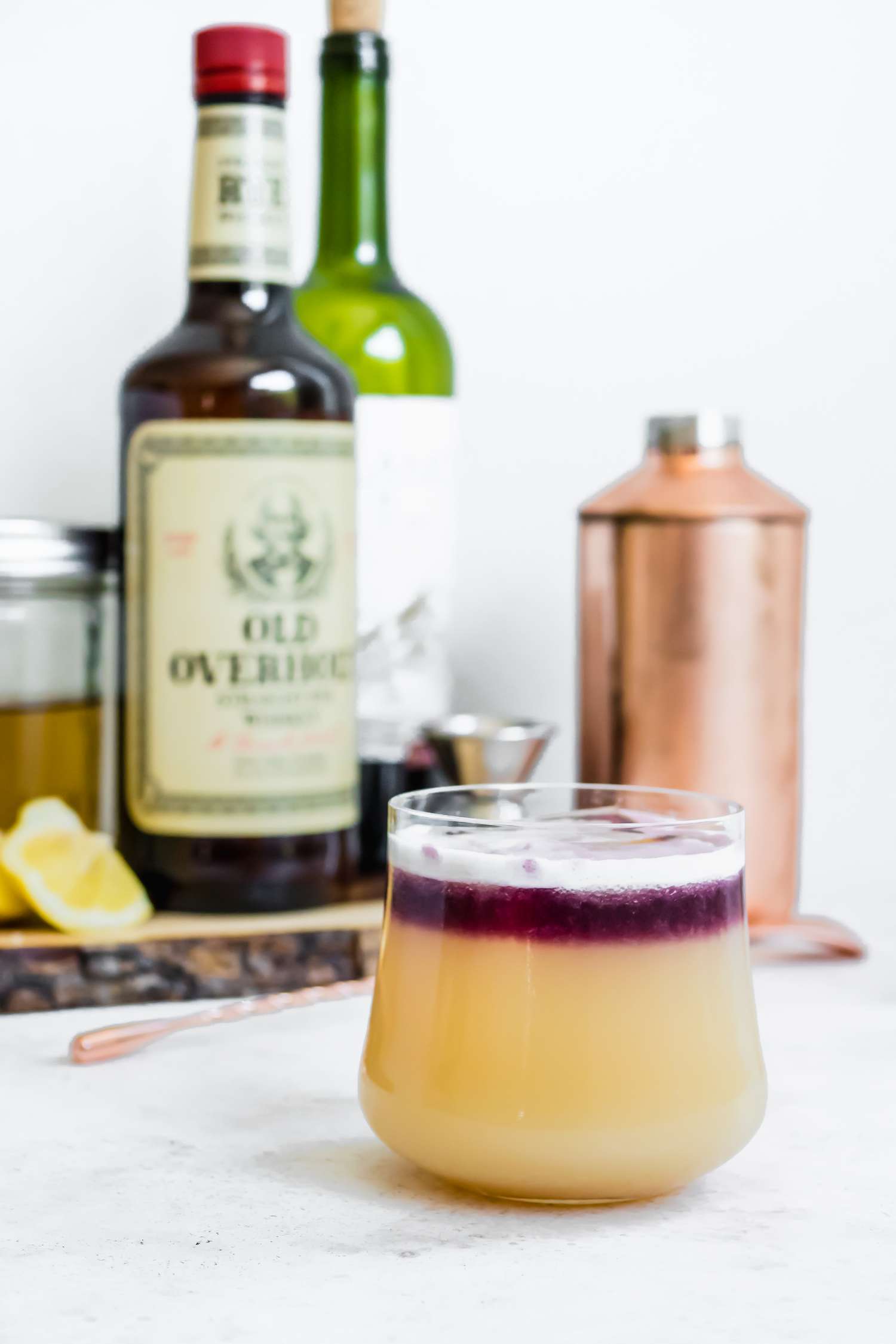 New York Sour Cocktail with Ingredients (Bottle of Whiskey, Lemon Wedges, Jar of Simply Syrup, etc) and Bartender Supplies in the Background