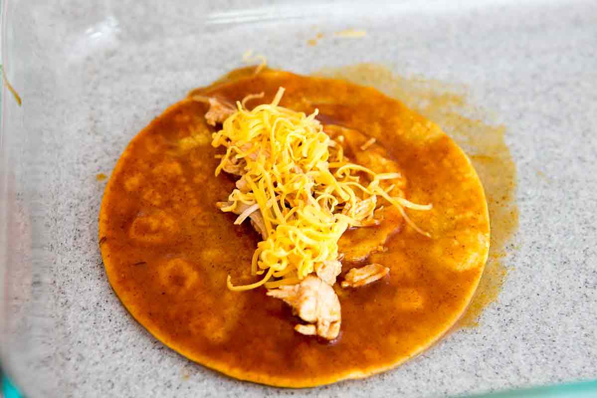 stuff chili dipped tortillas with cooked shredded chicken and cheese for easy chicken enchiladas