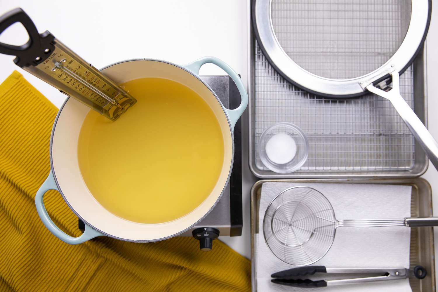 How to Deep Fry Set Up: a Thermometer in a Dutch Oven Filled with Hot Oil on a Portable Burner, and on Its Right, Two Trays (One Tray Lined with Paper Towels and Another Tray with a Wire Cooling Rack)