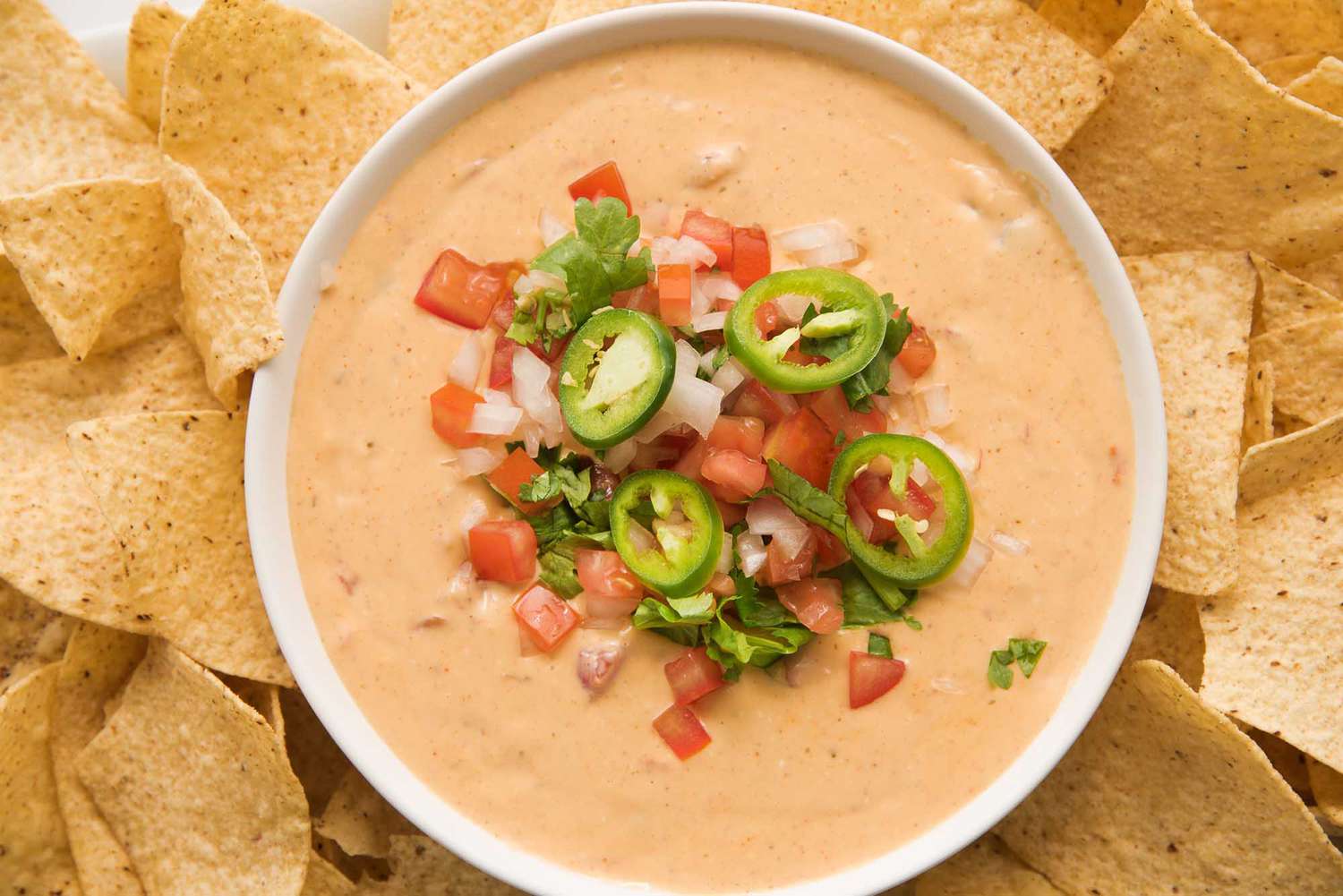 Get ready for game day with a bowl of ceamy queso dip topped with pico de gallo and surrounded by tortilla chips