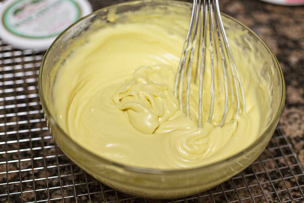 Zabaglione (whisked cooked egg yolks and sugar with rum) in a glass bowl with a whisk