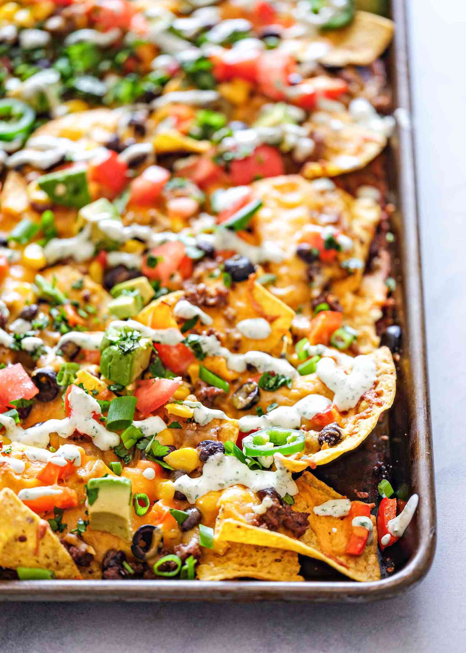 A pan of sheet pan nachos topped with spring onions