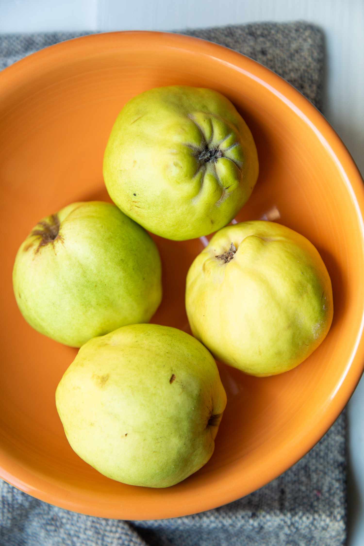 four quince fruits in an orange bowl