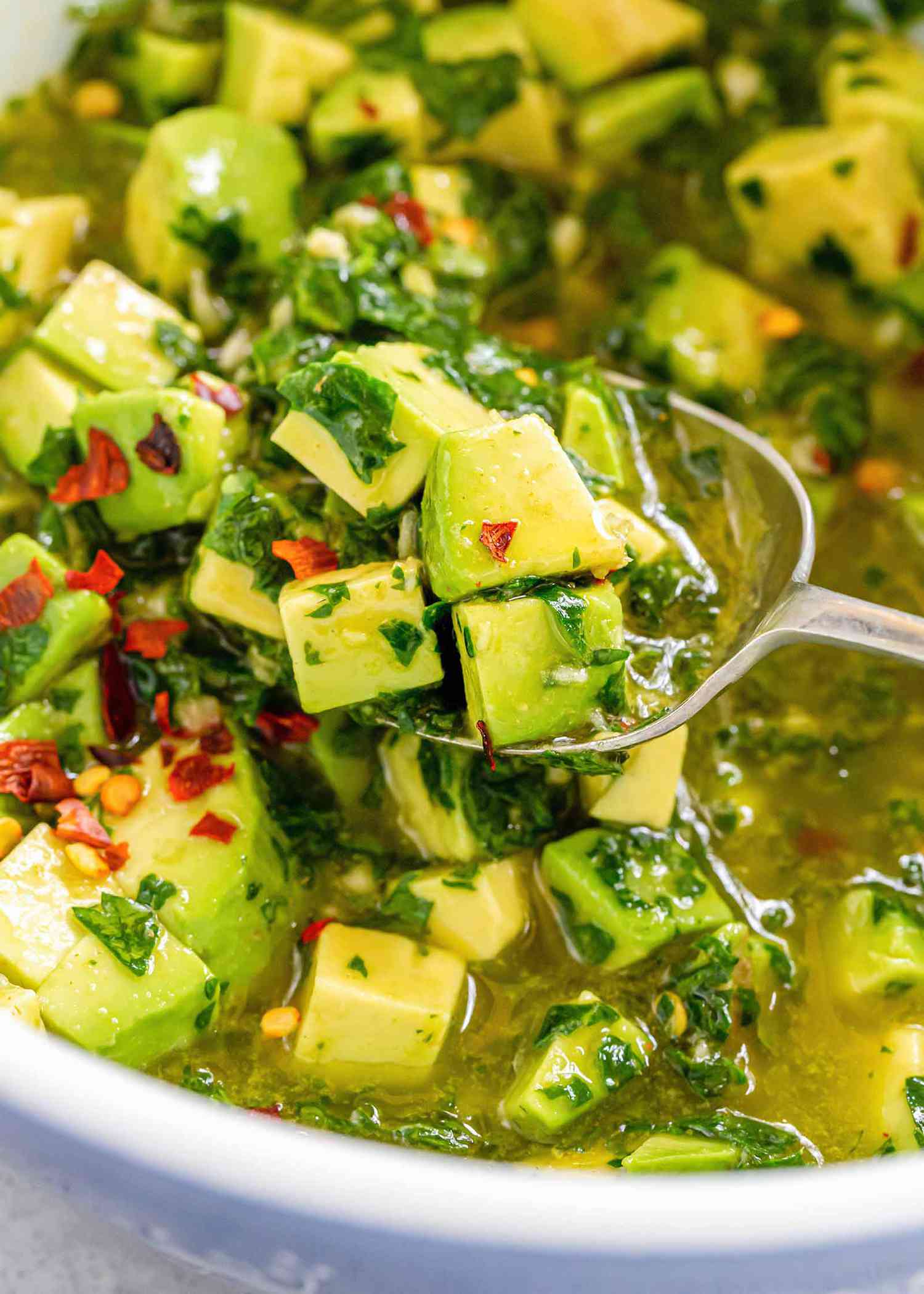 Avocado chimichurri to accompany skirt steak being lifted out of the bowl with a spoon for weeknight skirt steak