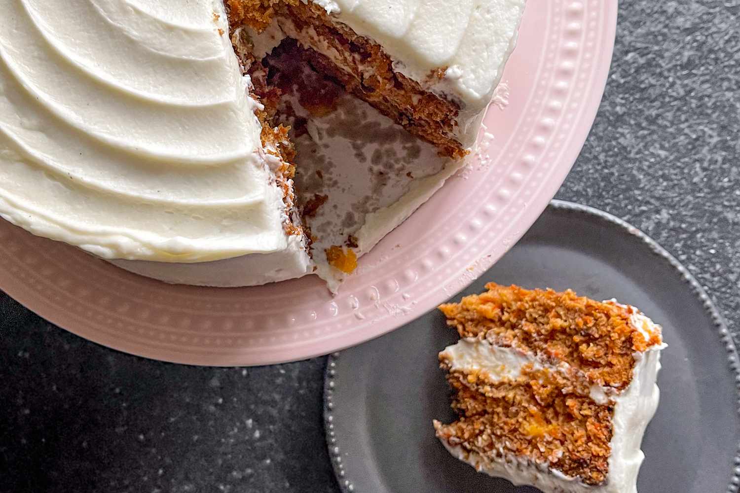 Overhead shot of a carrot cake with a slice cut out and placed on a plate next to it
