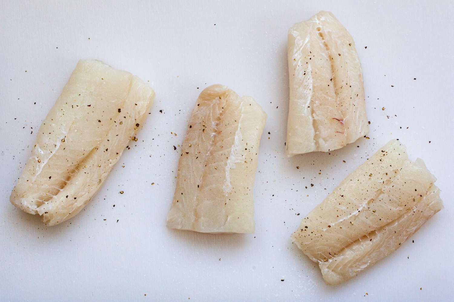 Raw fish fillets seasoned to make Crispy Oven Baked Fish Sandwiches.
