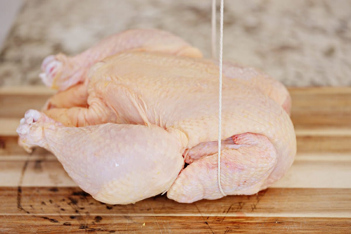 Truss a chicken with string pull the twine along the sides