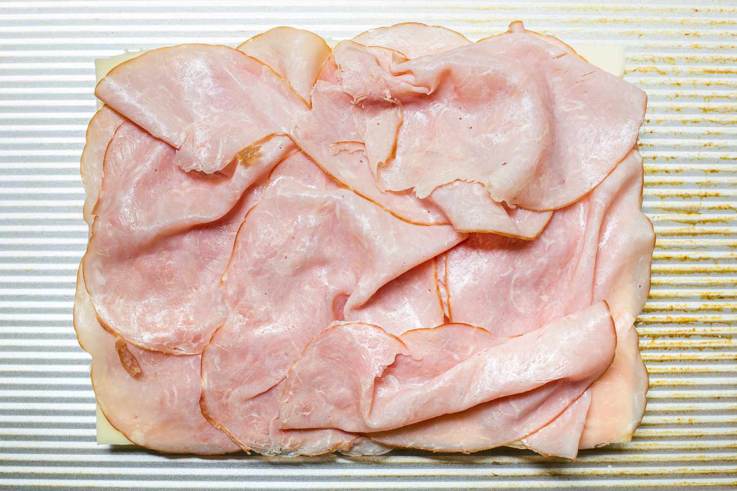 Bottom Half of Dinner Rolls Covered in Ham for Hot Ham and Cheese Sliders