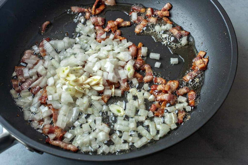 How to Cook Mussels in Tomato Sauce bacon, onions, and garlic cooking in pan