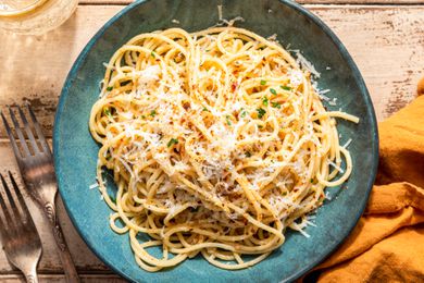 bowl of midnight pasta at a table with a drink, a table napkin, and utensils