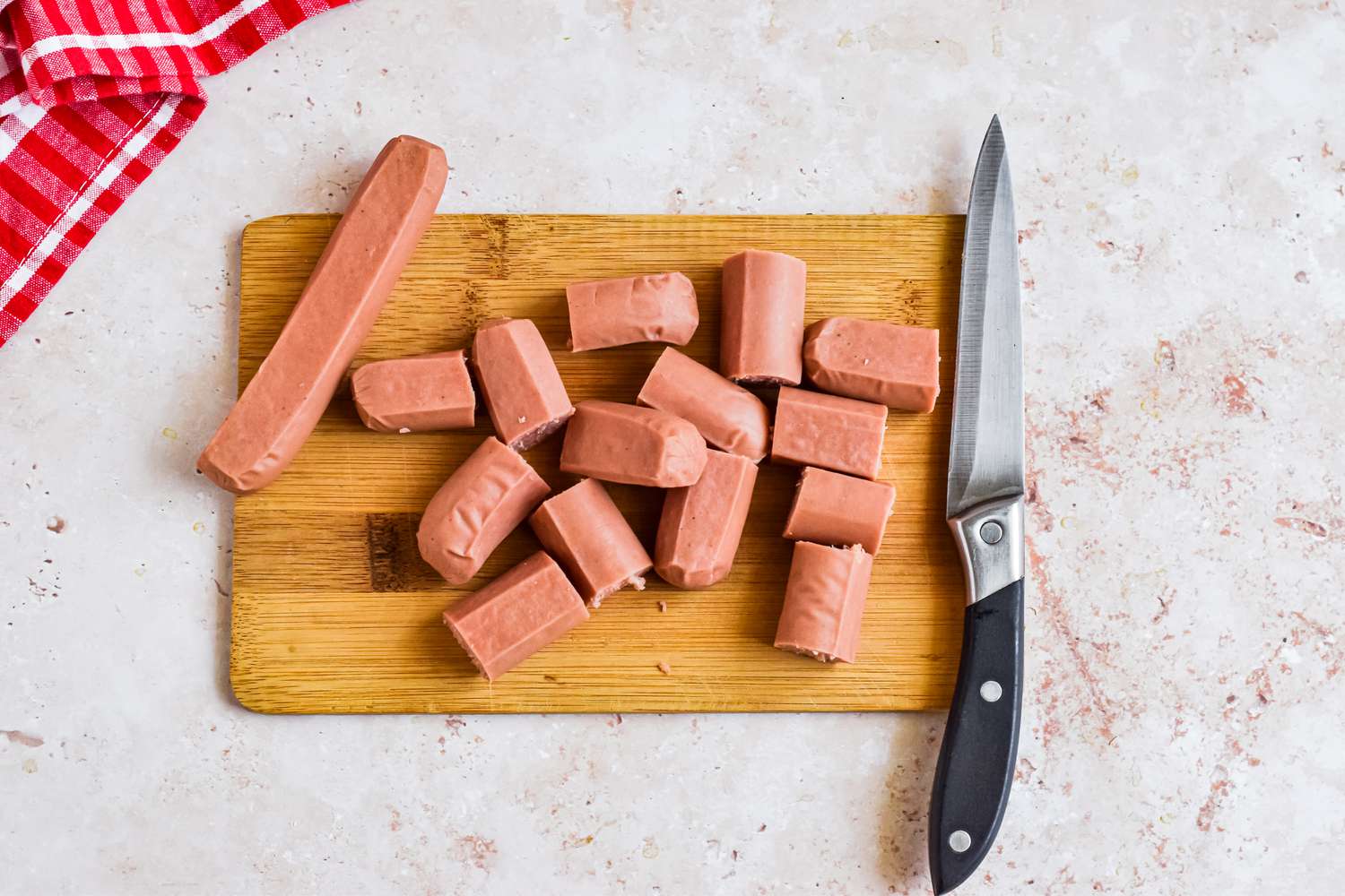 Hot Dogs Cut Into 1 inch Pieces on a Cutting Board Using a Knife