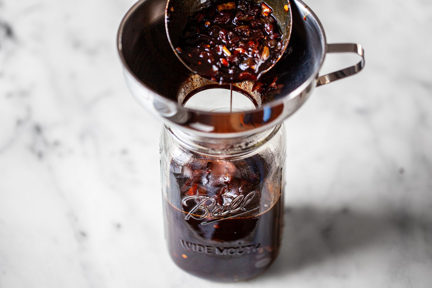 Homemade Worcestershire Sauce Transferred to a Mason Jar with a Funnel Attachment
