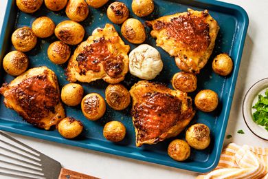 Overhead view of a baking sheet of roast chicken thighs and potatoes