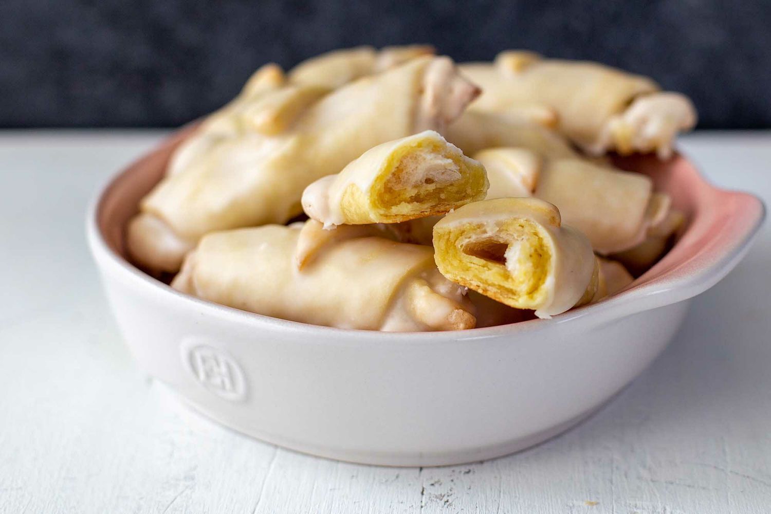 Butterhorn Christmas Cookies in a white bowl with one split in half revealing the filling.