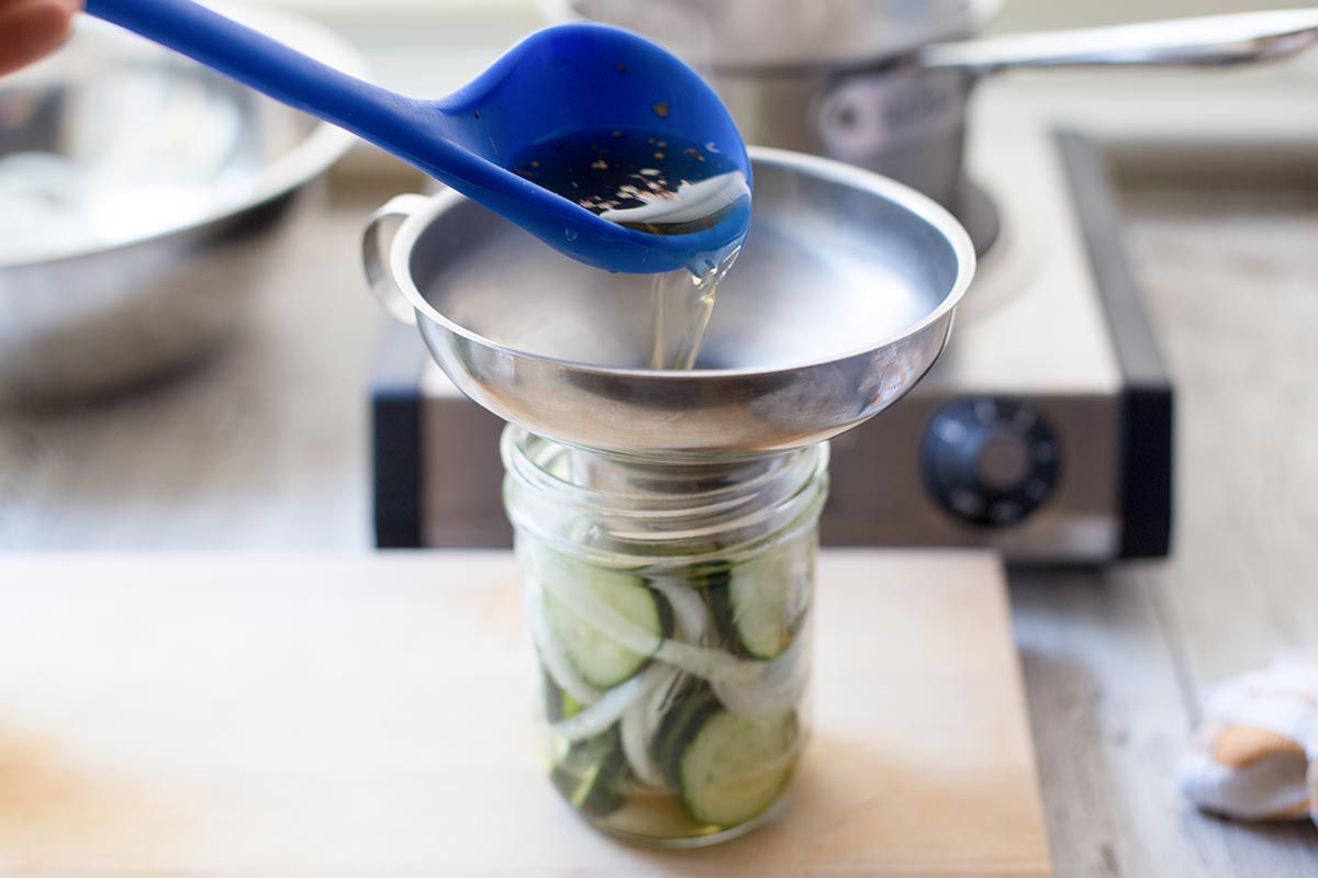 Ladle the hot pickling brine over the cucumbers and onions to make refrigerator pickles