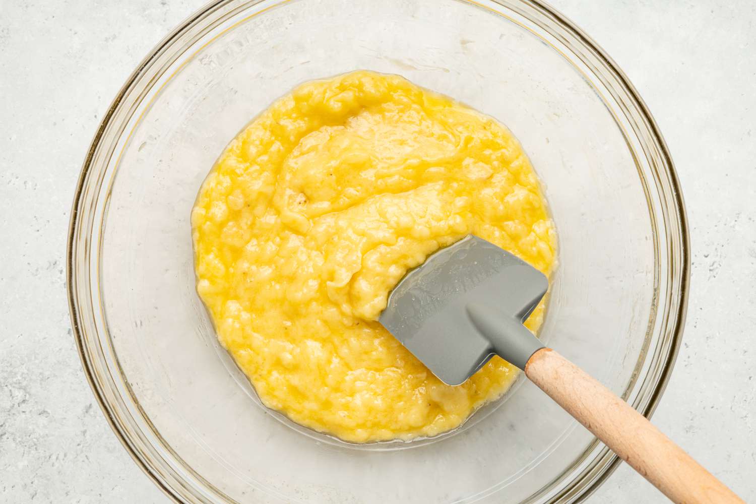 Melted Butter Mixed Into Bowl of Mashed Bananas Using a Spatula for Chocolate Chip Banana Coffee Cake