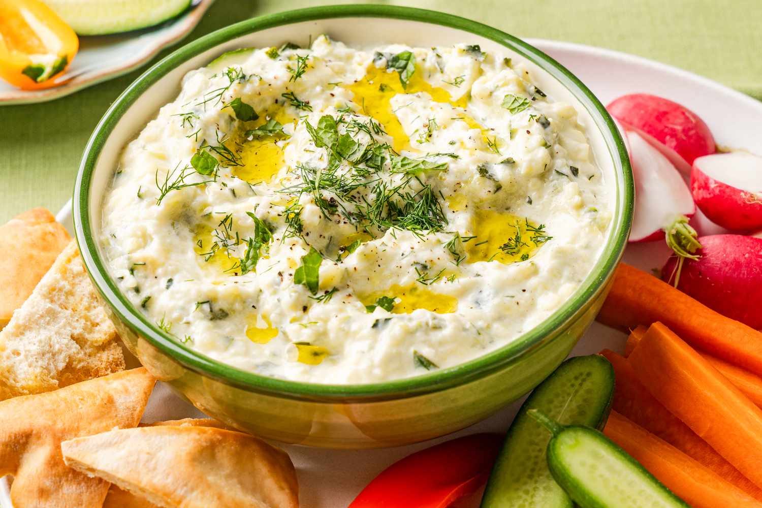 zucchini dip in a bowl on a plate with sliced vegetables