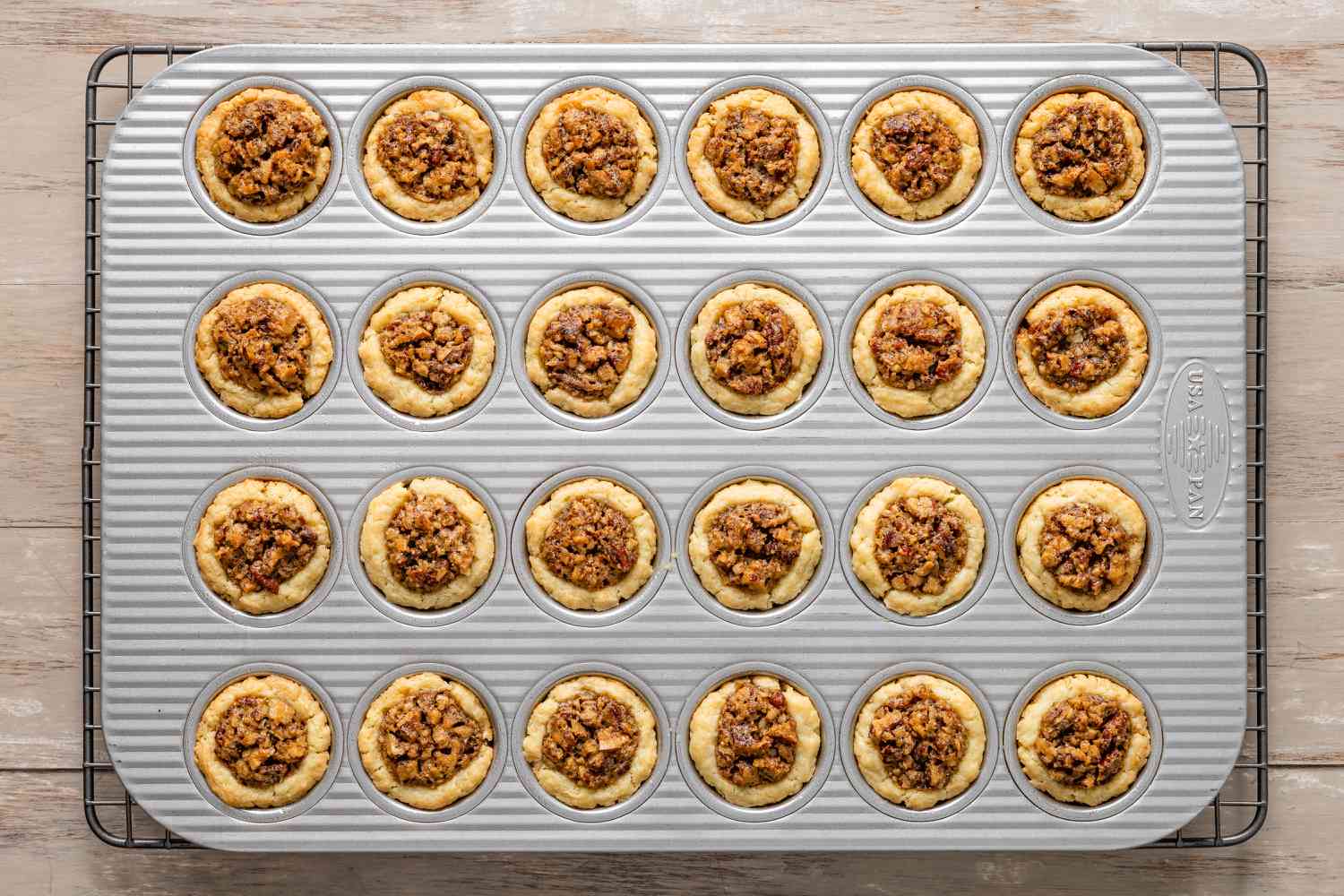 Pecan pie tassies on the muffin tin on a cooling rack