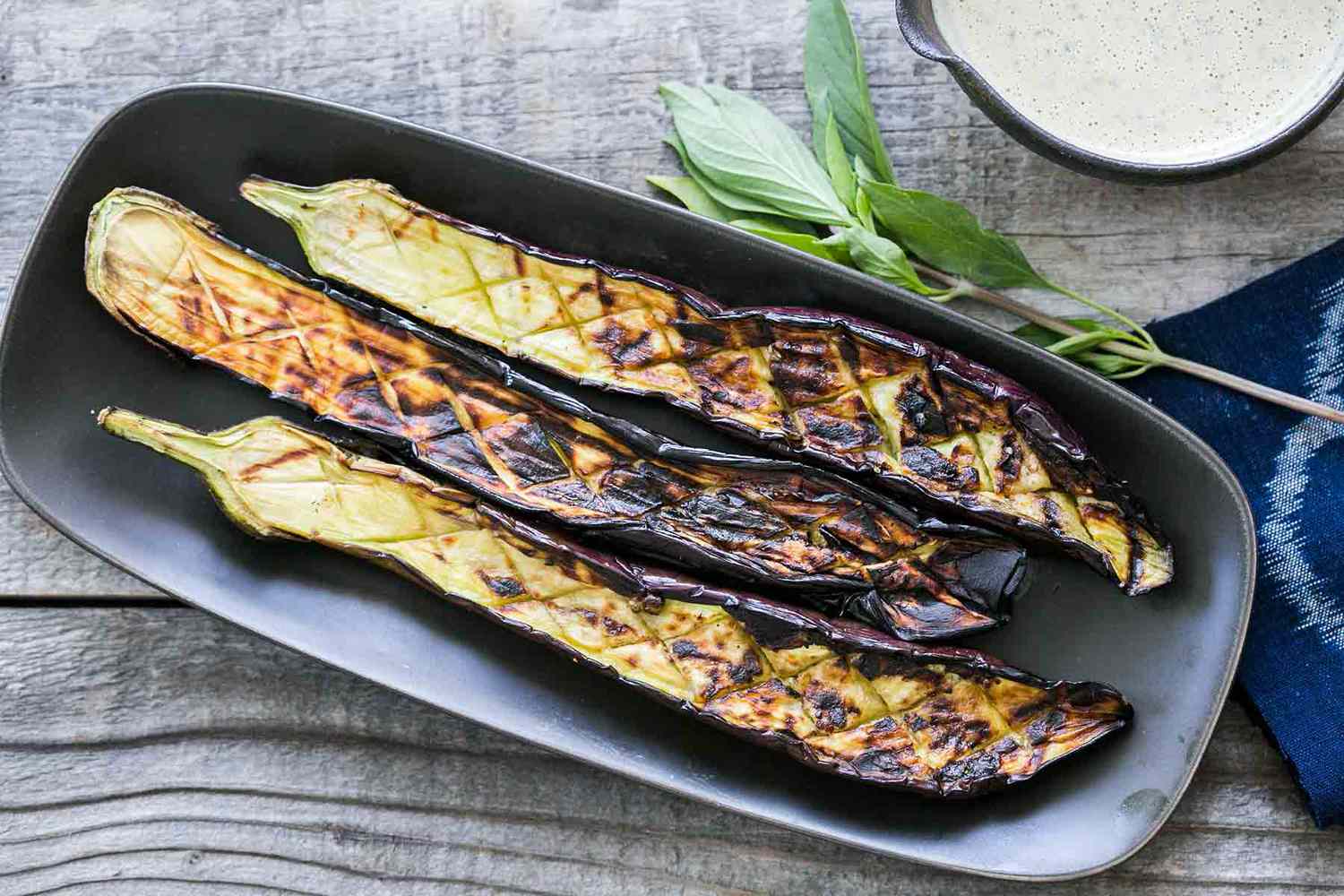 grilled japanese eggplant on a plate with a side of tahini sauce
