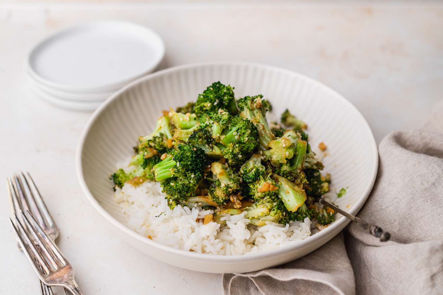 Side view of a bowl of stir fry broccoli served over rice.