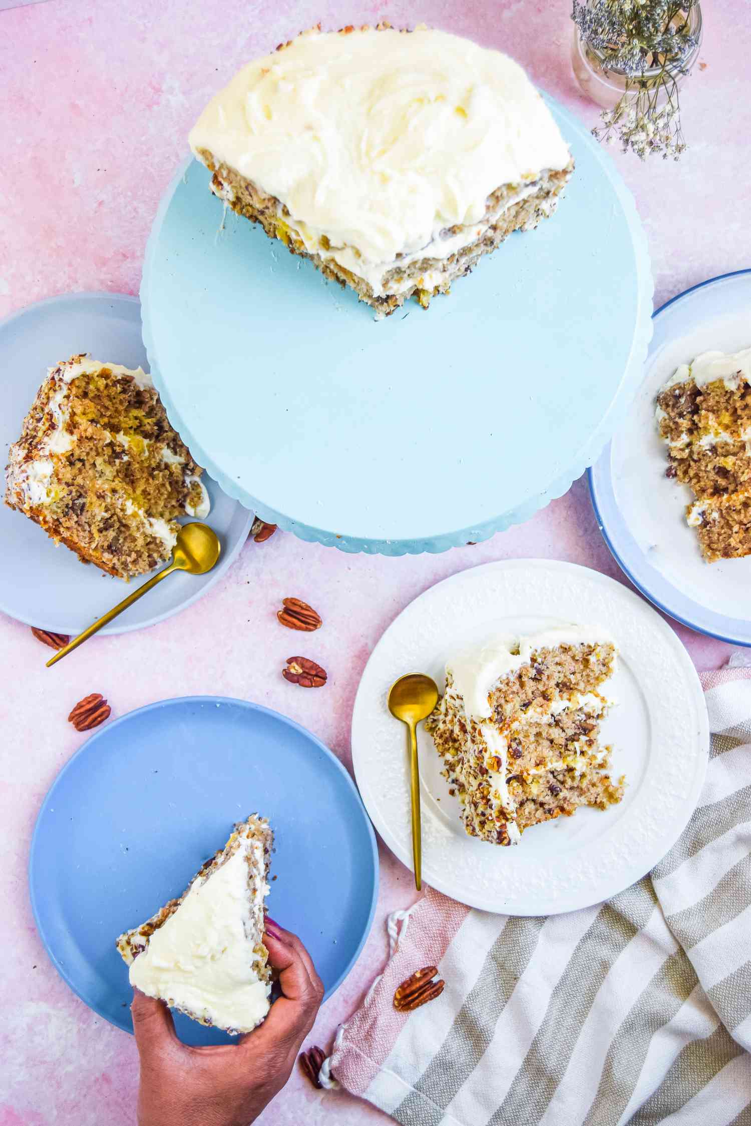 Overhead view of southern hummingbird cake on a blue cake stand and plates with slices on it.