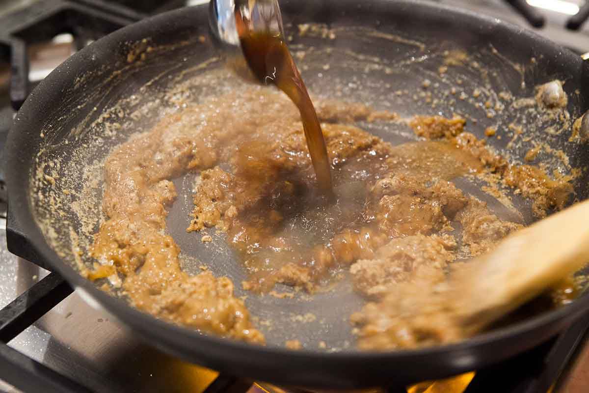 Stock being added to the meatball sauce