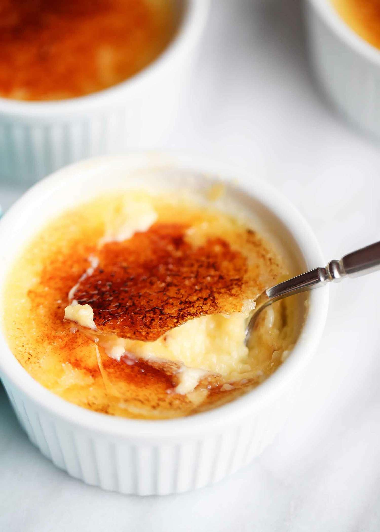 Crème Brûlée in a white ramekin with a spoon