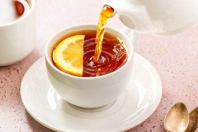 tea poured into a cup with a lemon 