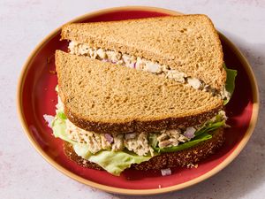 Tuna salad sandwich on whole grain bread, served on a red plate