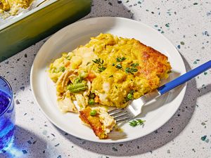 Angled view of a white plate of super easy chicken cobbler and fork on a speckled countertop