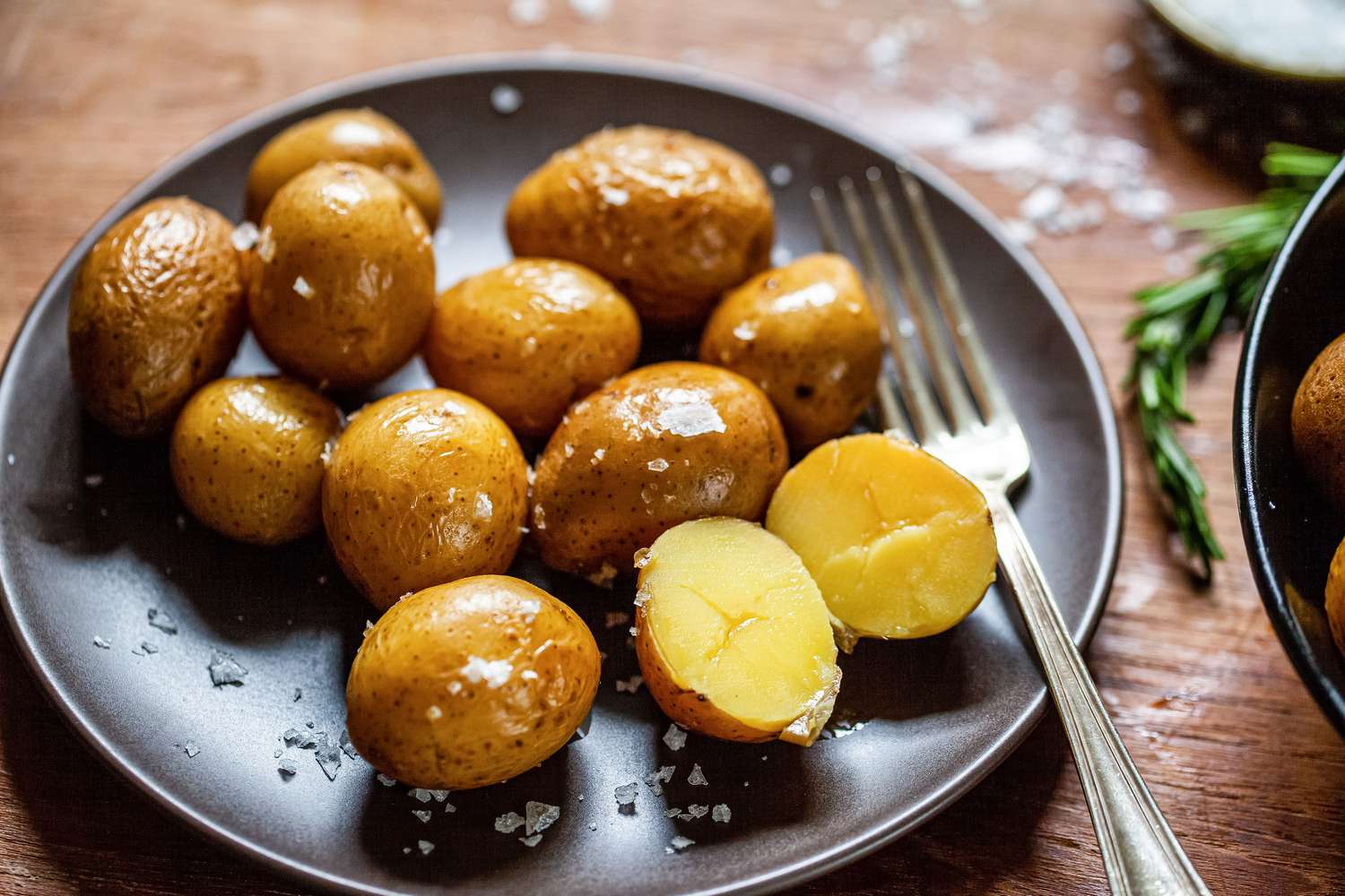 Potato confit on a black plate.