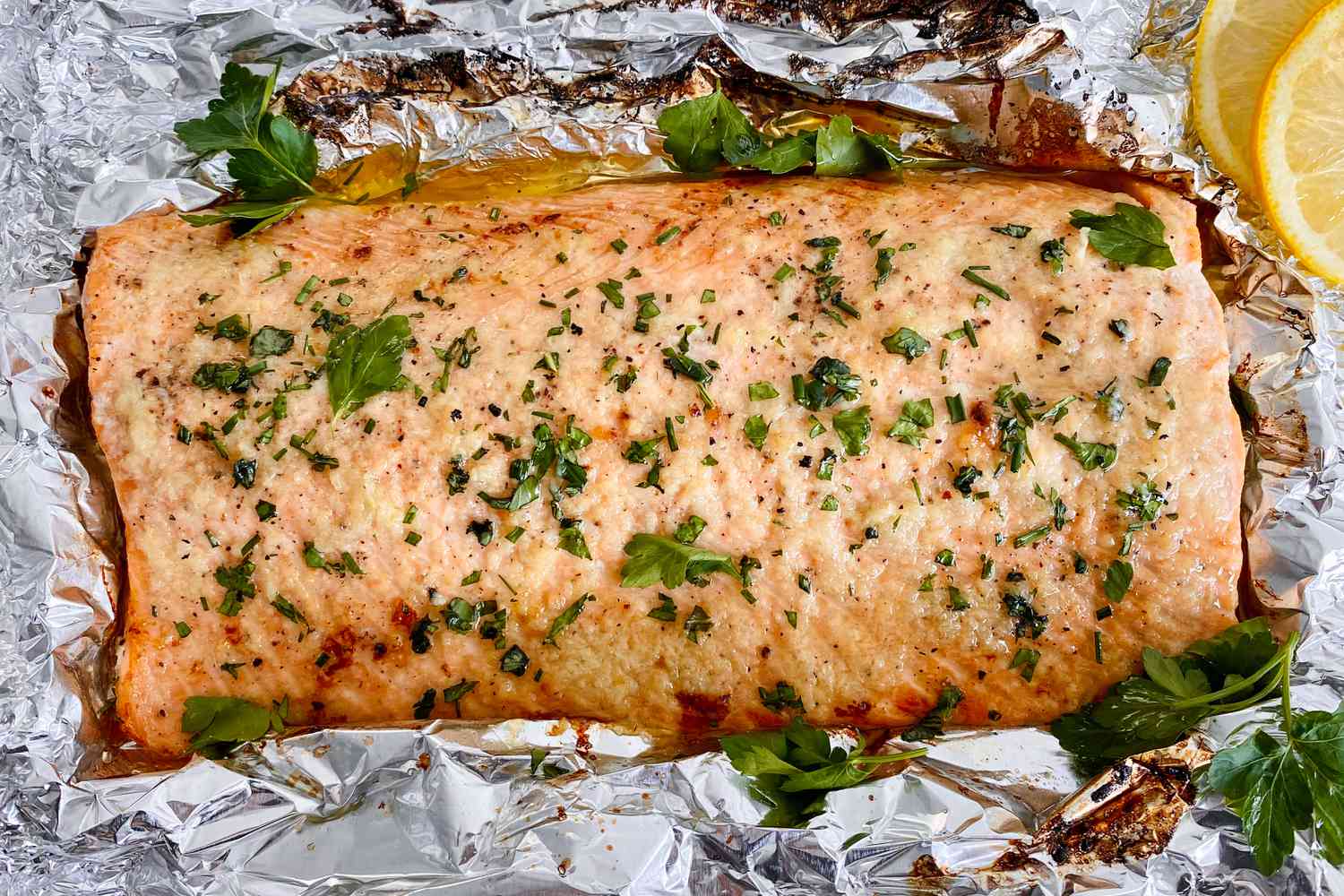 Garlic Butter Roasted Salmon topped with herbs and set on foil.