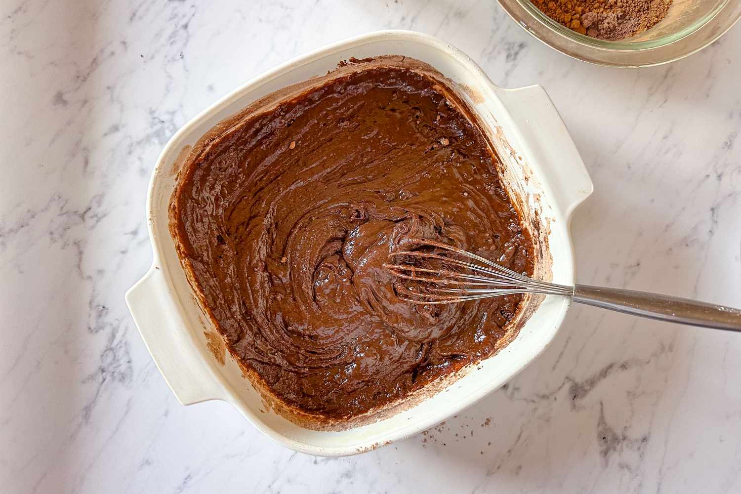 cake batter in a baking dish all mixed together with a small whisk Samantha Seneviratne's 10-Minute Microwave Chocolate Pudding Cake