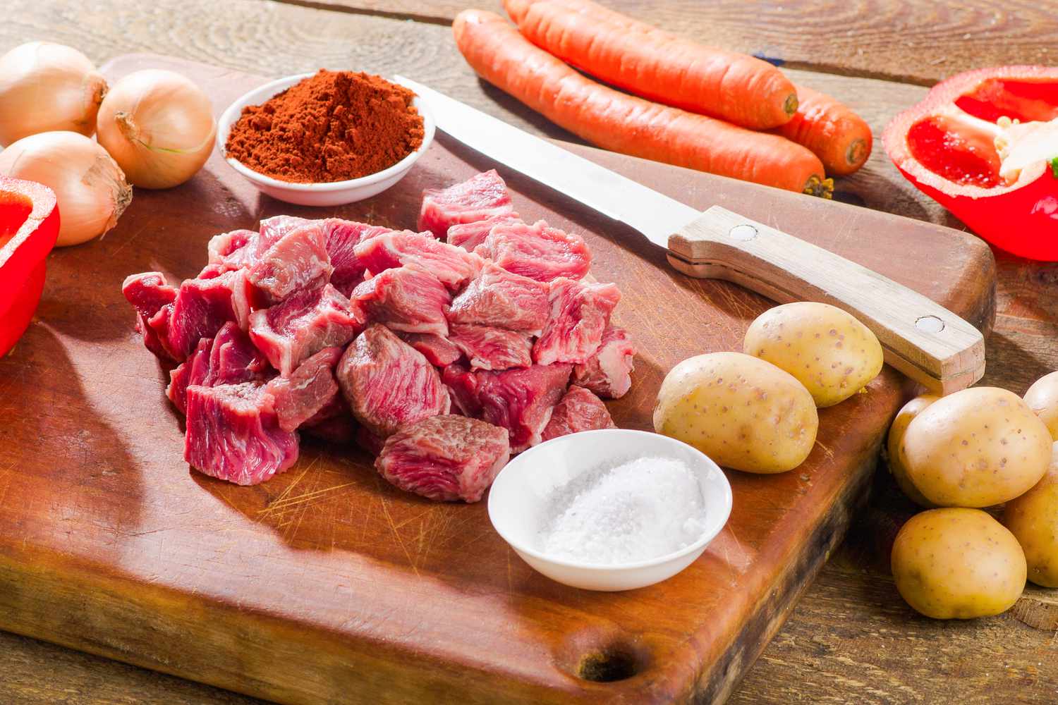 Ingredients for beef stew on a wooden cutting board