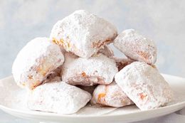Pile of Powdered Sugar Covered Beignets on a Plate 