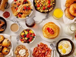 A variety of breakfast items including pancakes, waffles, fruit, eggs, and croissants