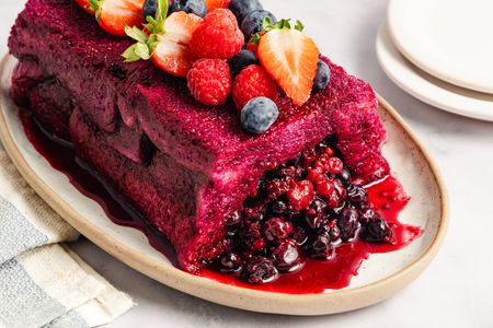 A summer pudding topped with various berries served on a platter