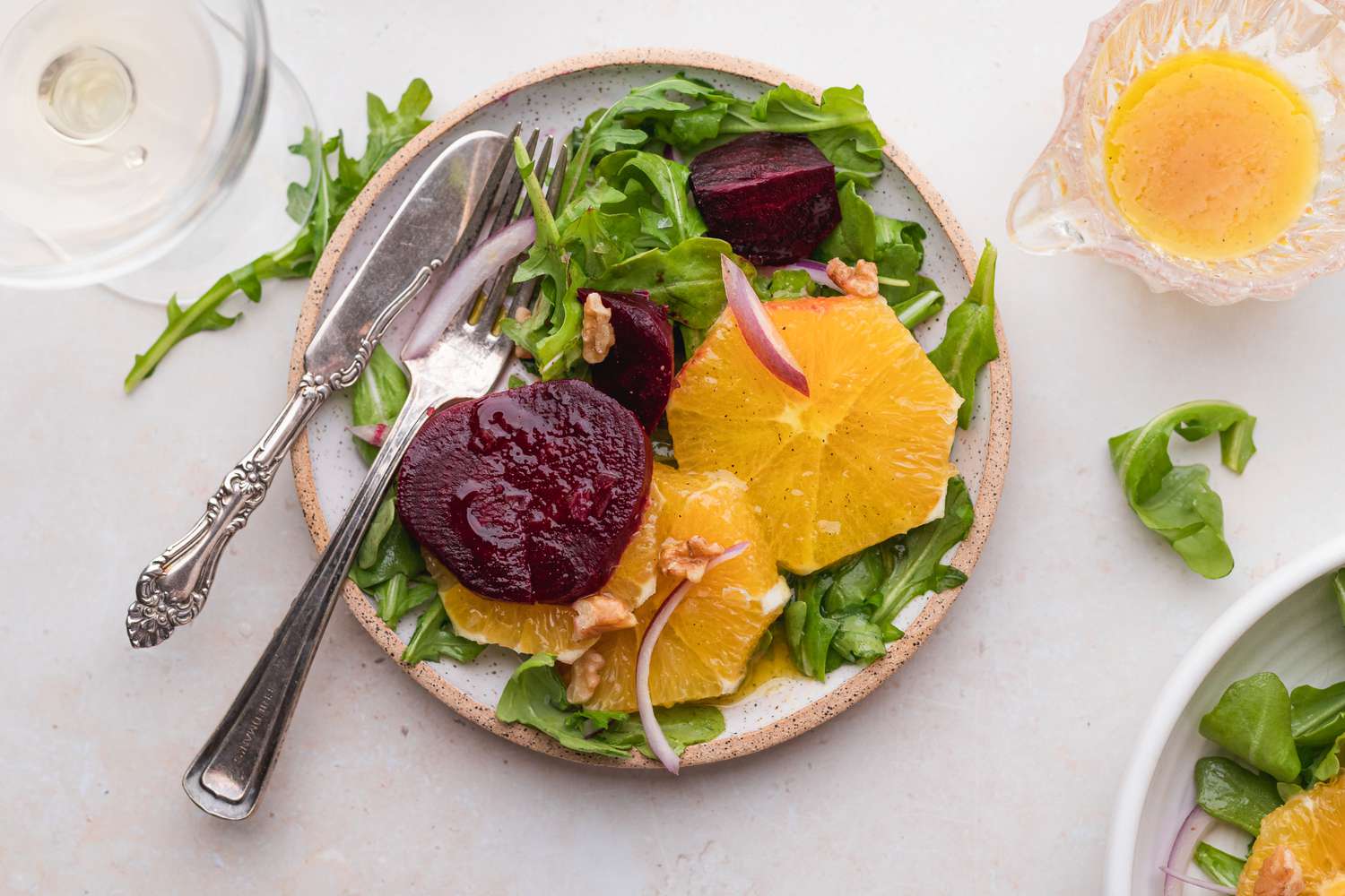 Pouring vinaigrette over a salad of beets and oranges.