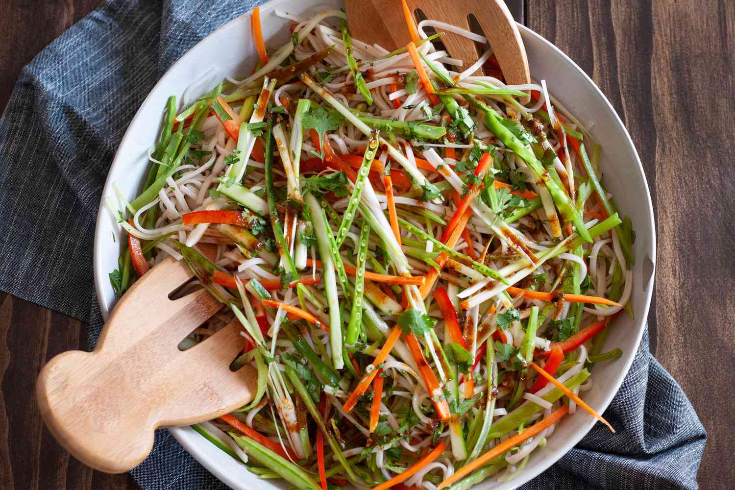 Overhead view of an easy rice noodle salad in a serving bowl along with wooden claws.