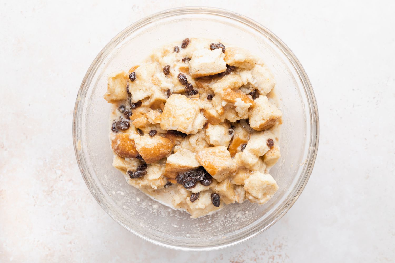 A glass bowl with soaked bread and raisins