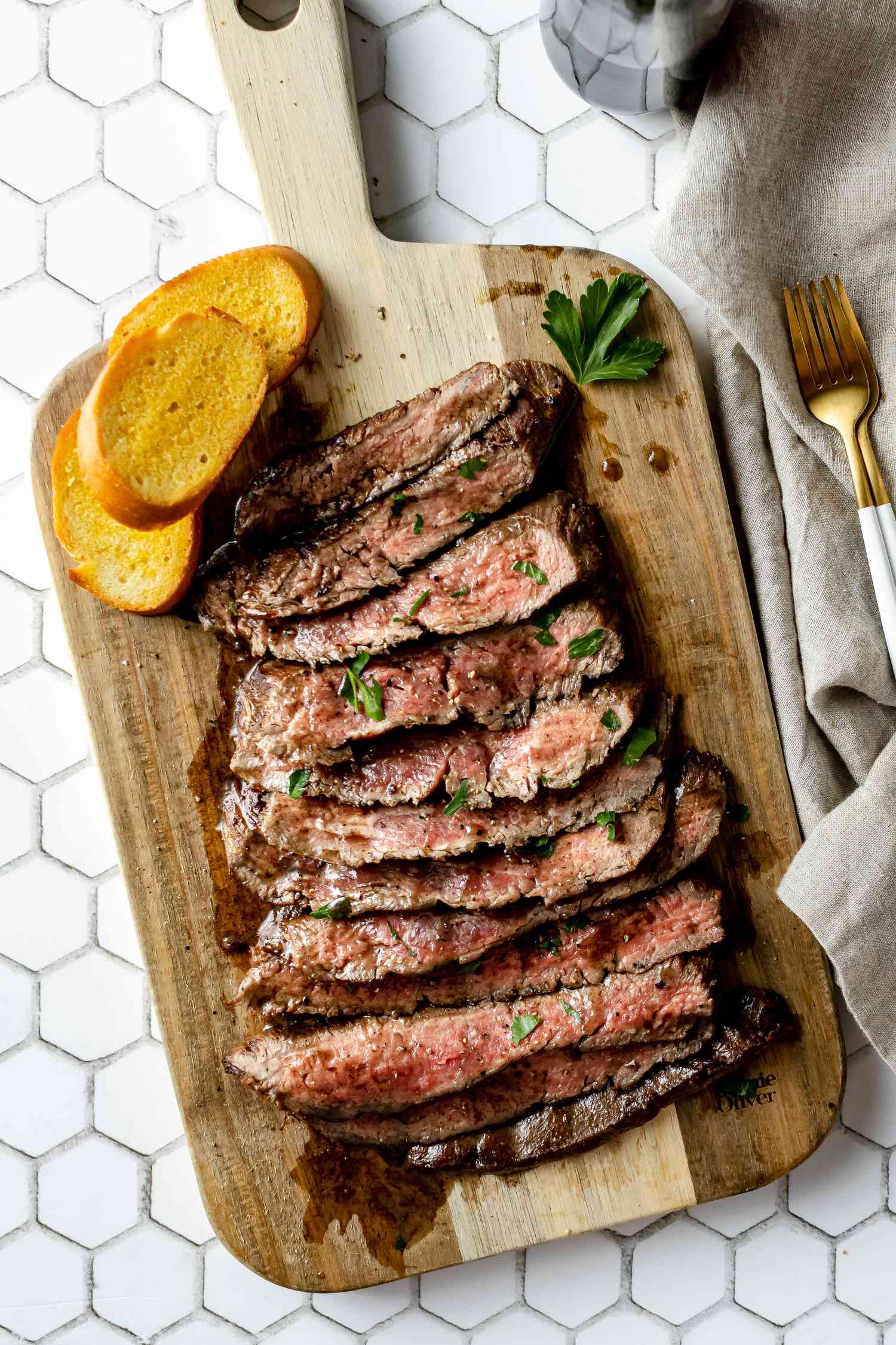 Overhead view of a flank steak sliced on a cutting board.