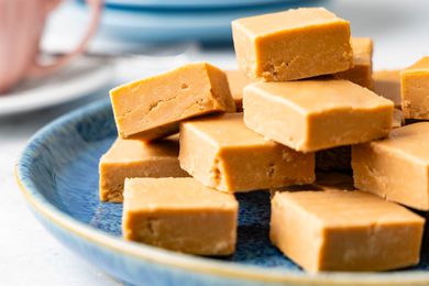 Penuche on a plate, and in the background, a teacup and a stack of plates