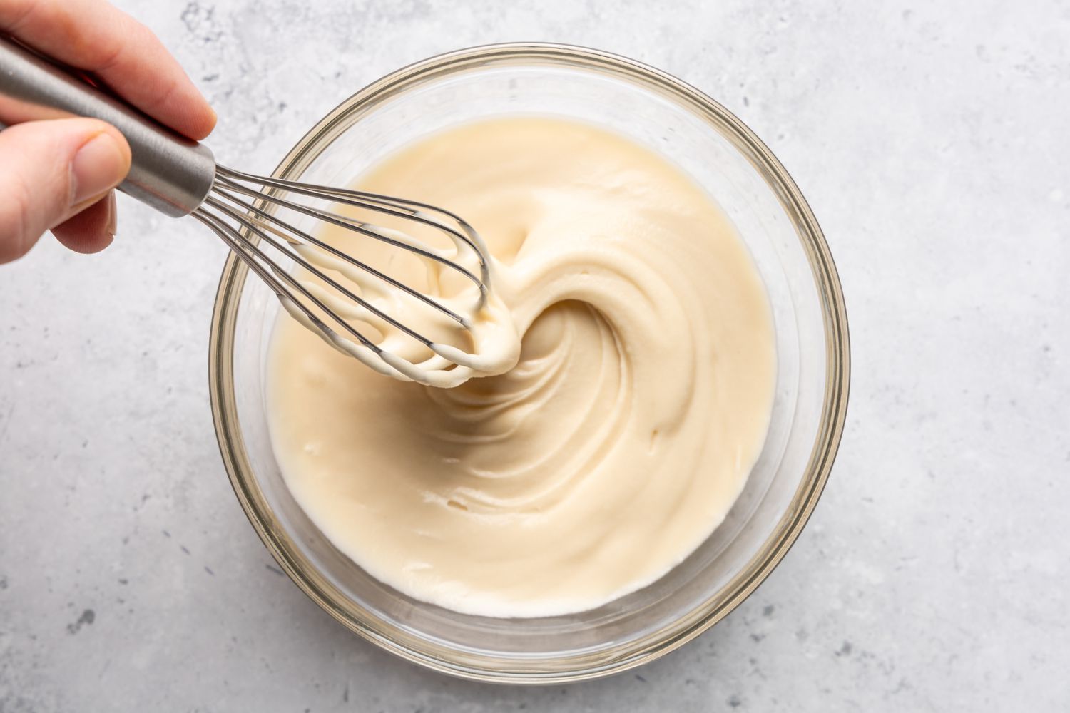 A hand holding a whisk making the glaze for the Chocolate stout loaf cake recipe