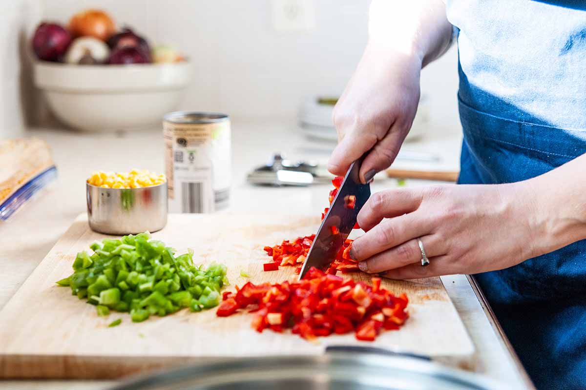 Skillet Chicken Dinner Recipes - woman chopping a red bell pepper with a knife