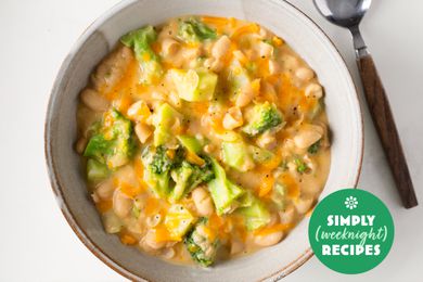 Broccoli and cheese white beans in a pale serving bowl with a spoon on the side