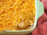 Corn pudding in a casserole dish (with a bit already spooned out from the corner) next to a table napkin