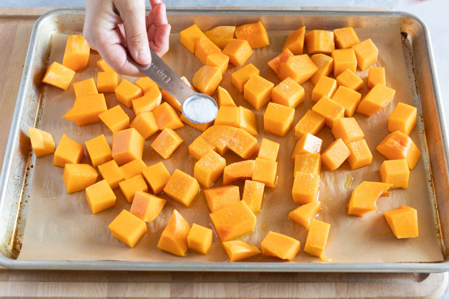 Seasoning cubed butternut squash with salt
