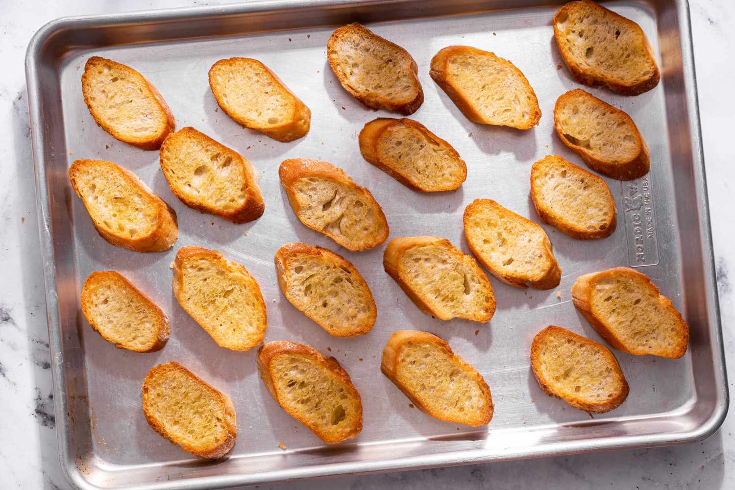 Toasted baguette slices on a baking sheet for bruschetta recipe