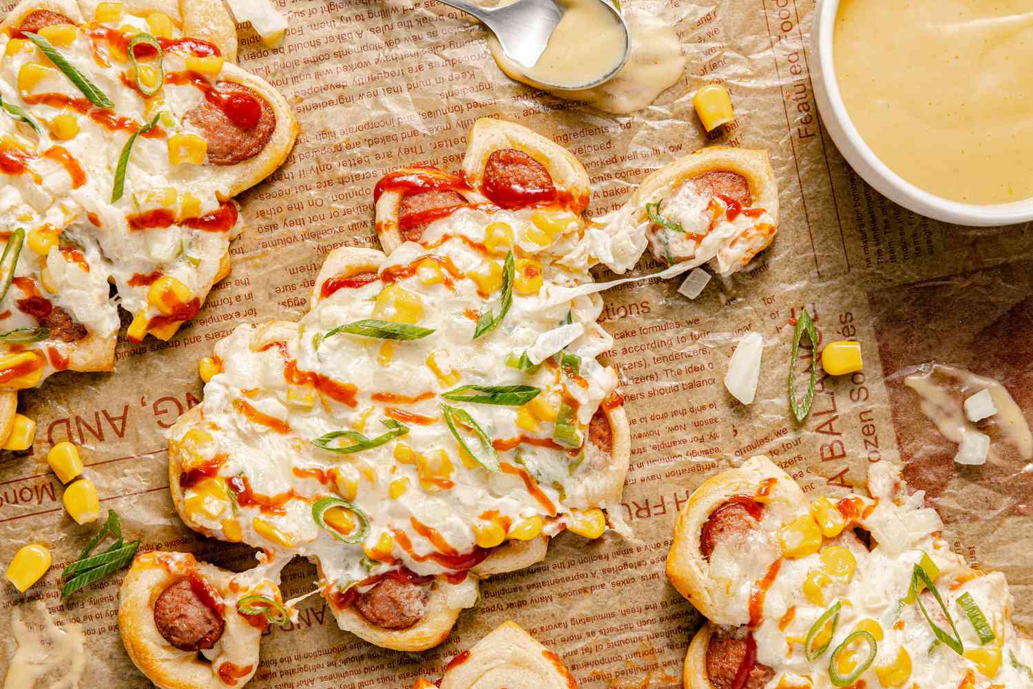 Pull-Apart Corn Cheese Pigs in a Blanket with a Piece Pulled Off Surrounded by More and a Bowl of Mustard